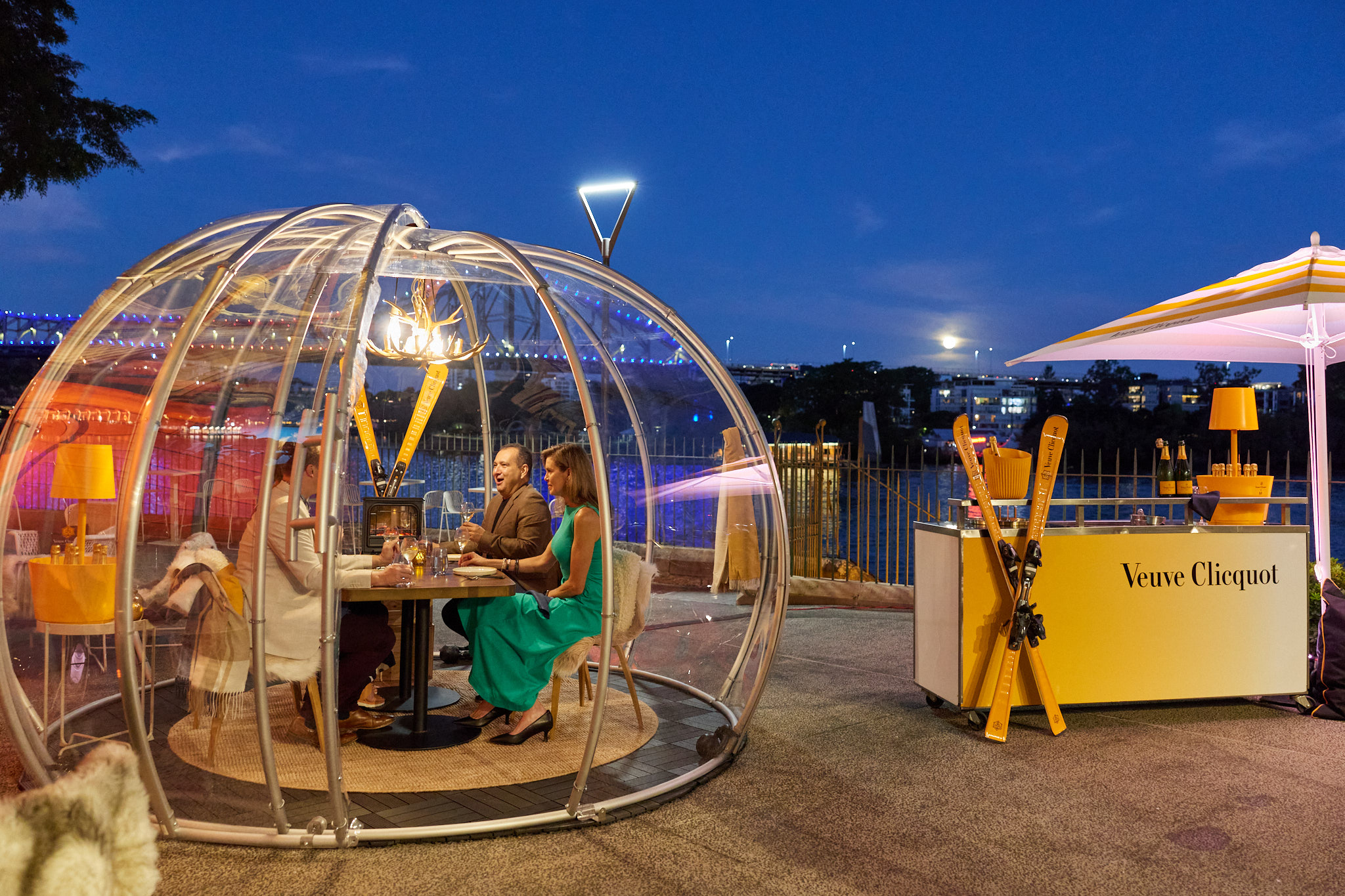 Group of friends dine in an alpine 'igloo' themed dome at a riverside restaurant in Brisbane